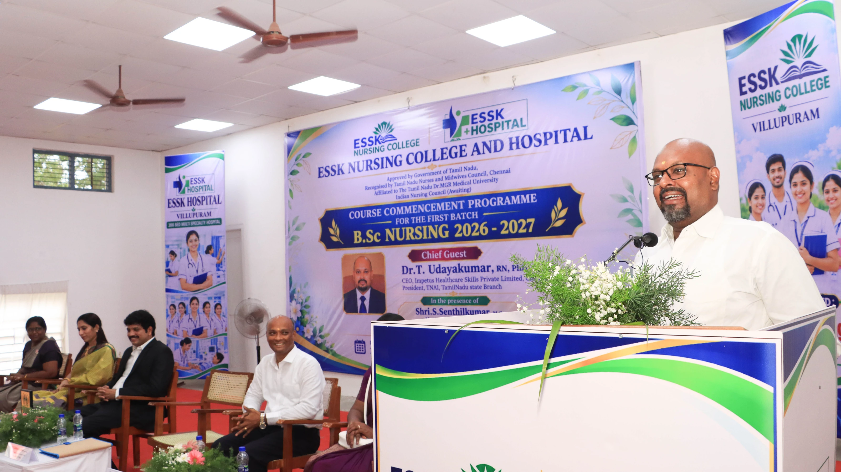 The chief guest speaks at a lectern in front of the programme banner