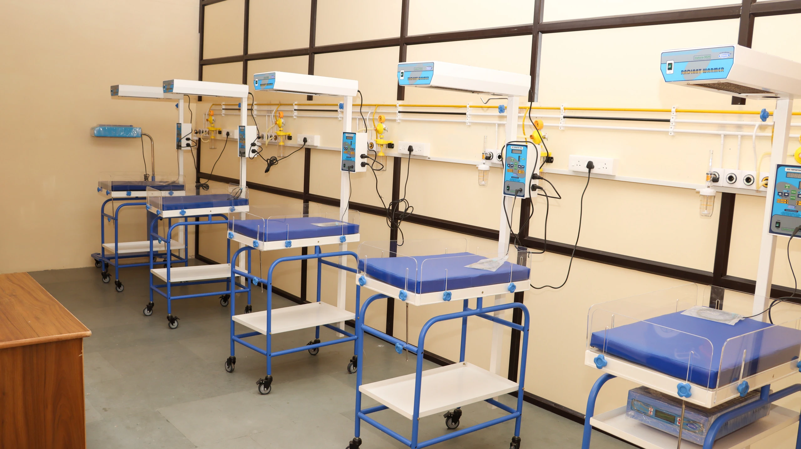 A newborn care unit with a row of baby warmers