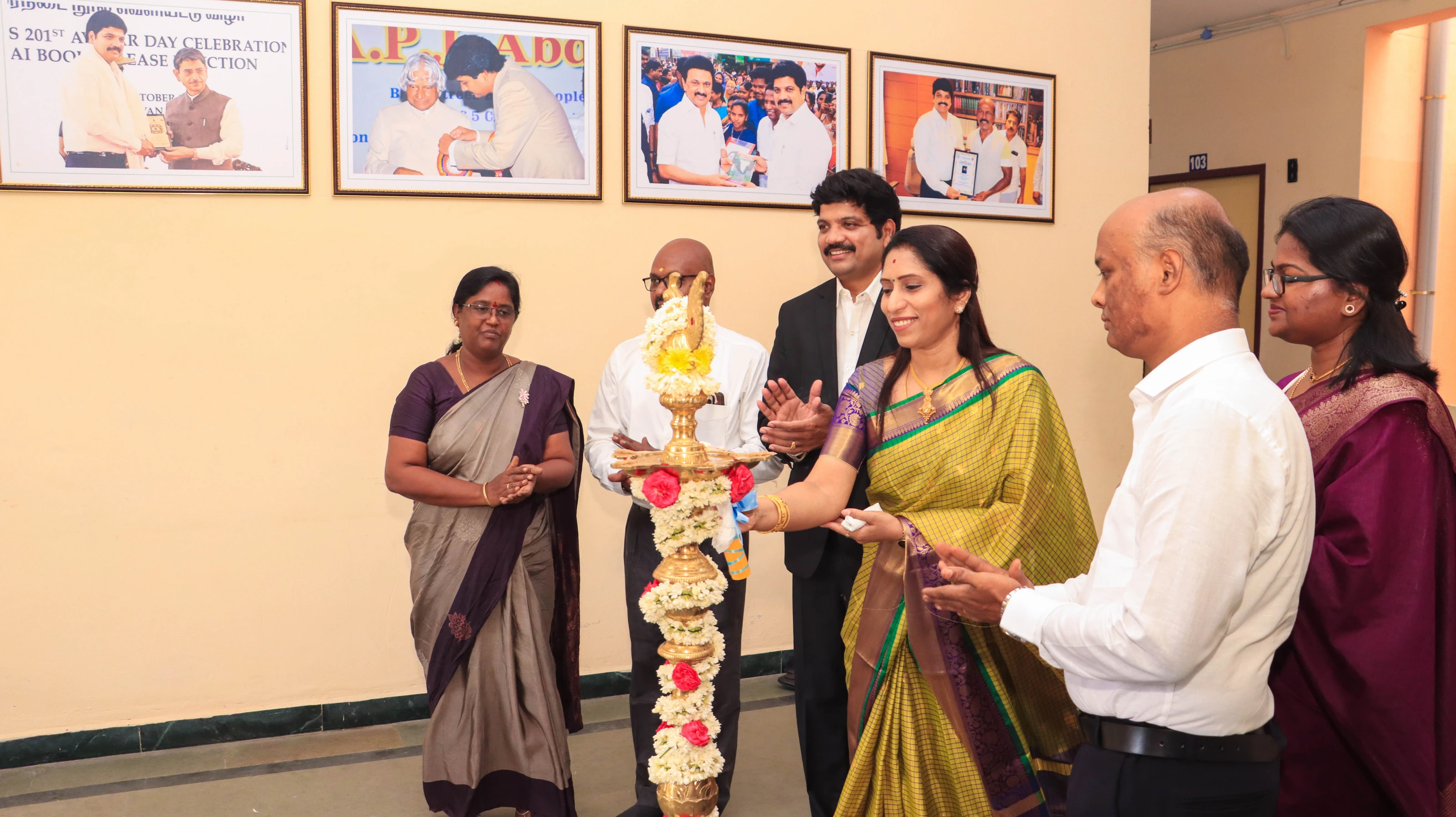 Guests and staff light a traditional brass lamp decorated with flowers